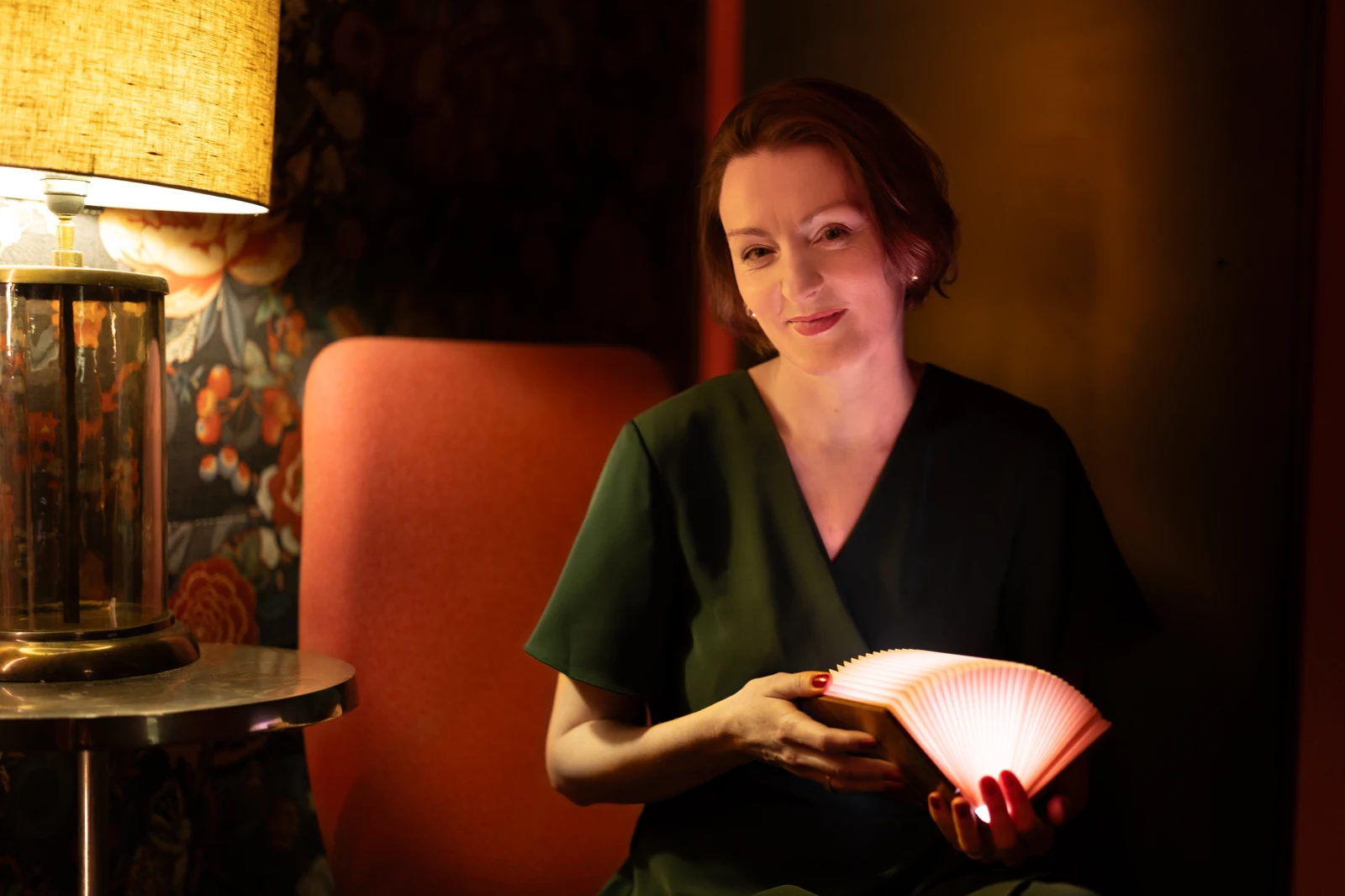 Marie-Luise Steiner mit leuchtendem Buch im warmen Lampenlicht — erzählerische Portraitaufnahme